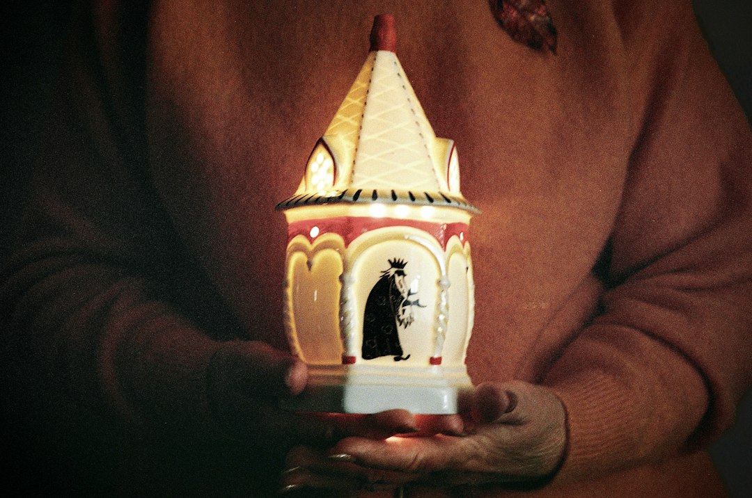 Person holding a glowing decorative lantern with a figure inside