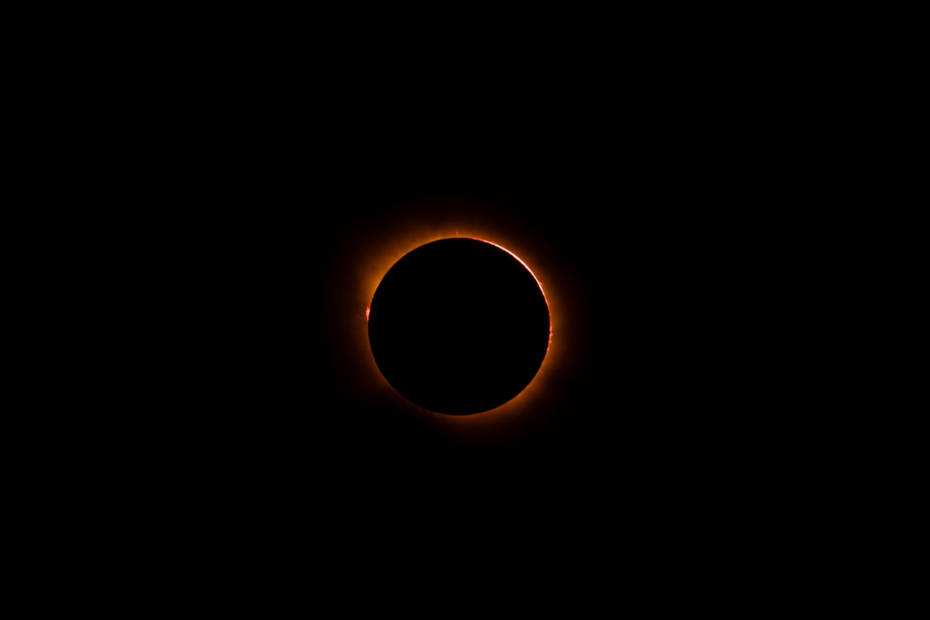 New Moon in Leo - Stunning solar eclipse viewed in the night sky, captured in Spain with vibrant orange corona.