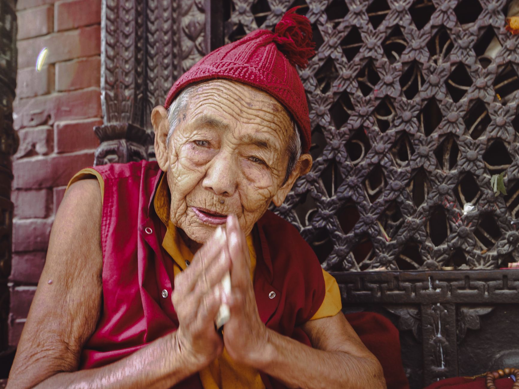 An elderly monk in traditional attire prays, embodying spirituality and devotion.