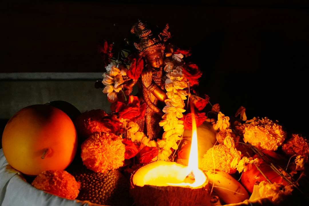 Traditional idol with a lit lamp and offerings in darkness