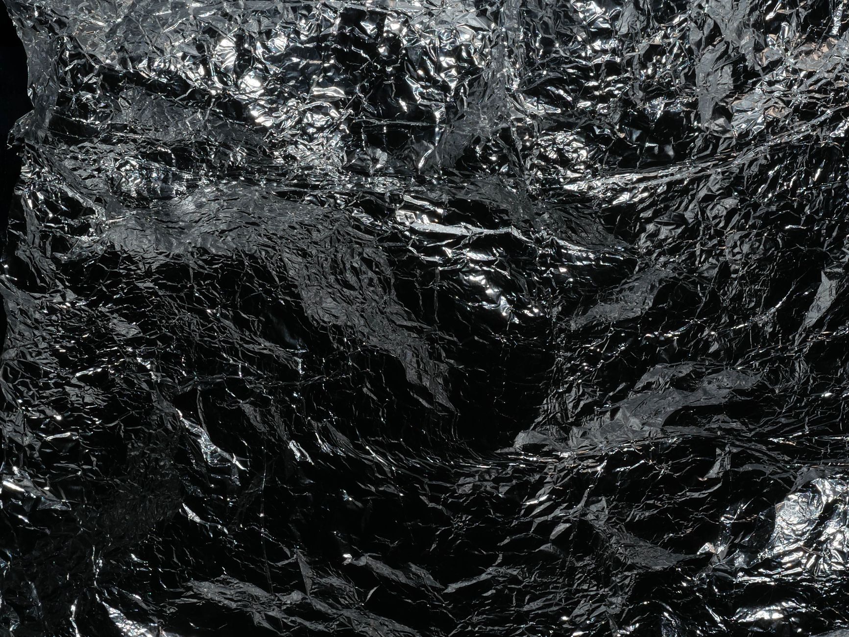 Reflective crumpled silver foil texture, ideal for backgrounds or abstract designs.