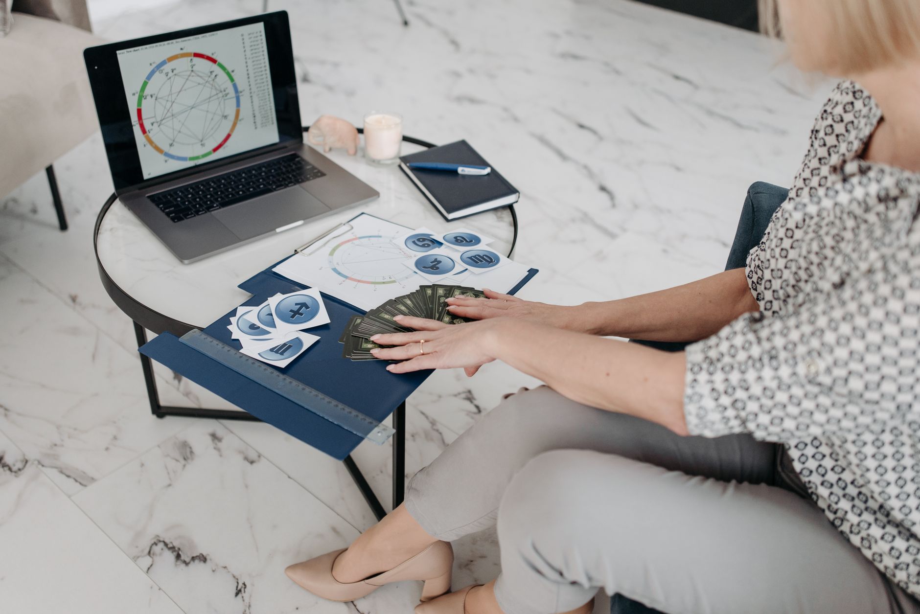Astrology scene with a woman using a laptop and tarot cards in a modern living room.